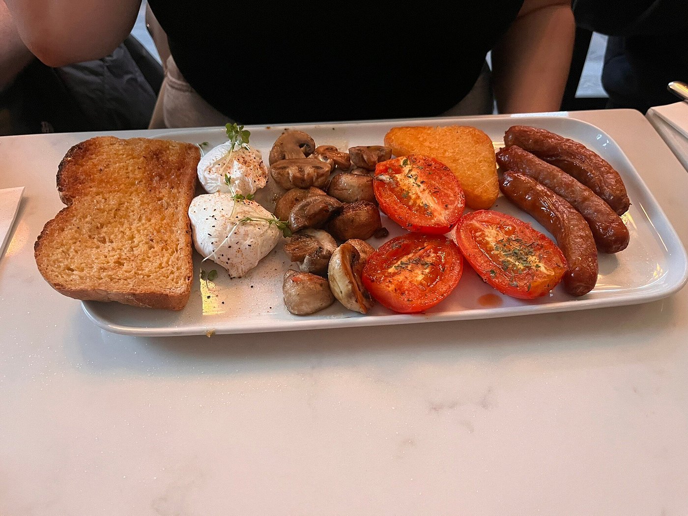 Custom breakfast with poached eggs, sausages, mushrooms, grilled tomatoes, hash brown, and toast.