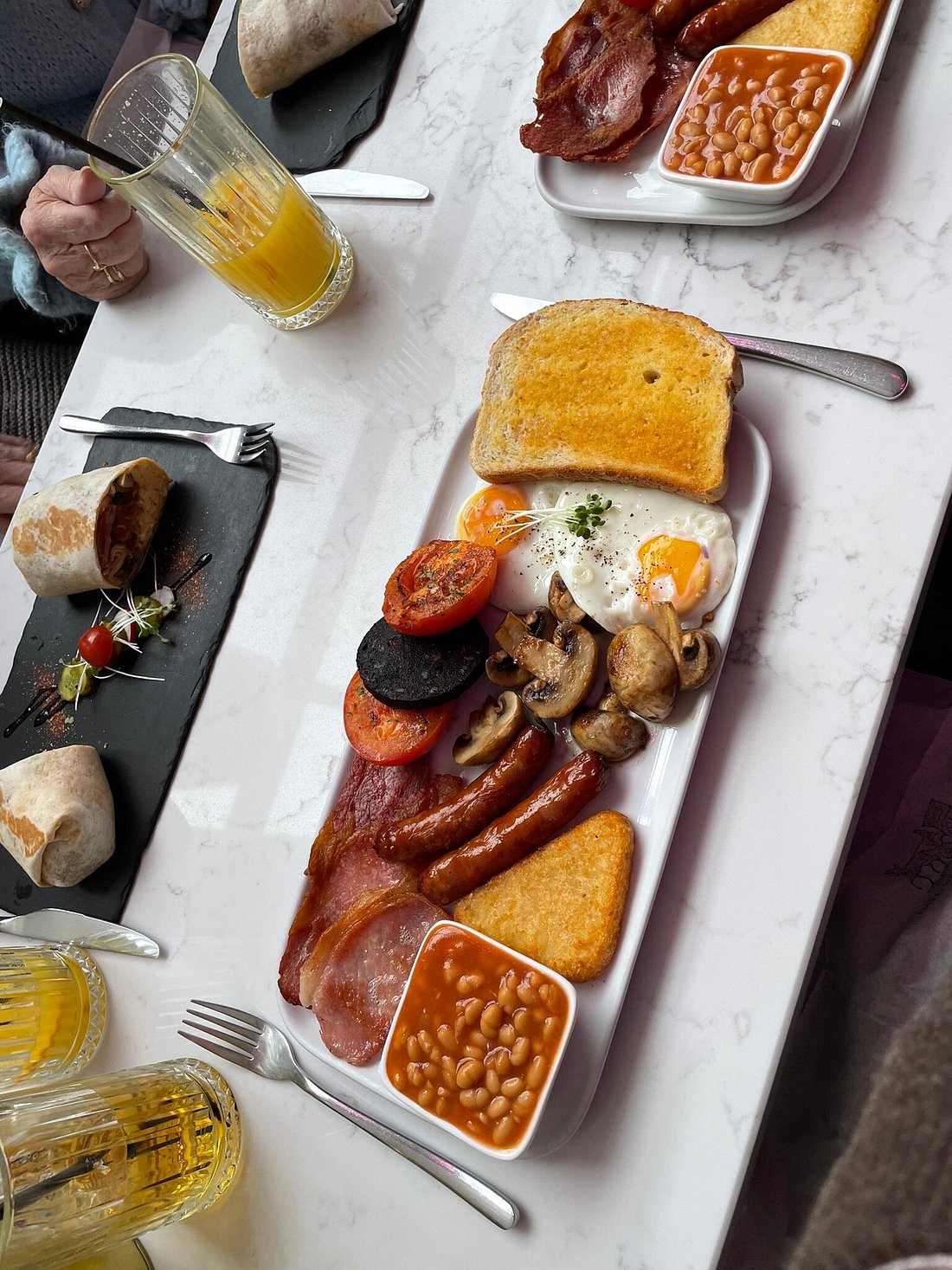 Full English breakfast with eggs, sausages, bacon, toast, baked beans, and breakfast wraps.