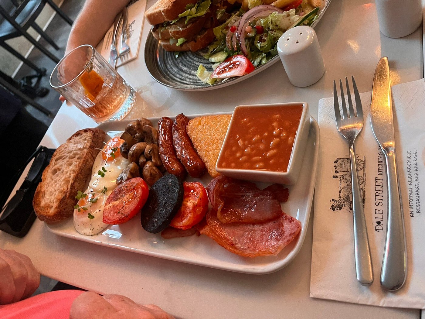 Full English breakfast with eggs, toast, beans, sausage, bacon, black pudding, mushrooms, and tomato.