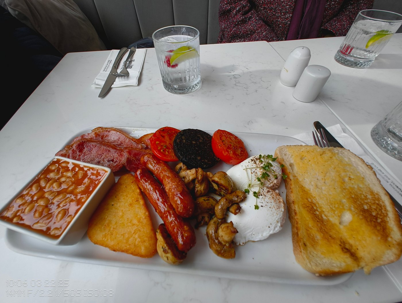 Full English breakfast with toast, poached eggs, sausages, bacon, black pudding, grilled tomato, hash brown, mushrooms, and baked beans.